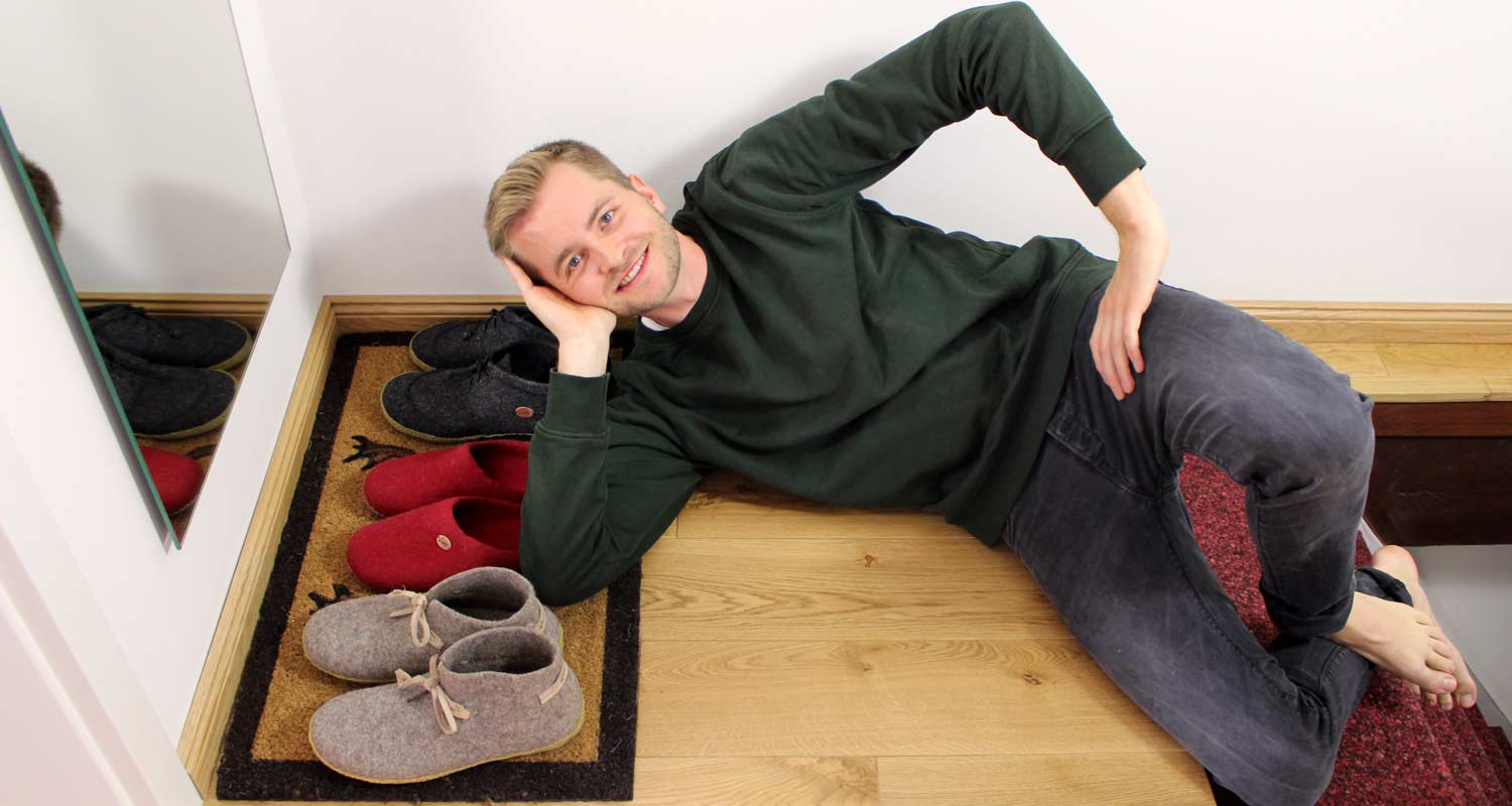 WoolFit Interview mit Benni Spree zum Thema Nachhaltigkeit liegend im Eingang vor einigen Filzhausschuhen